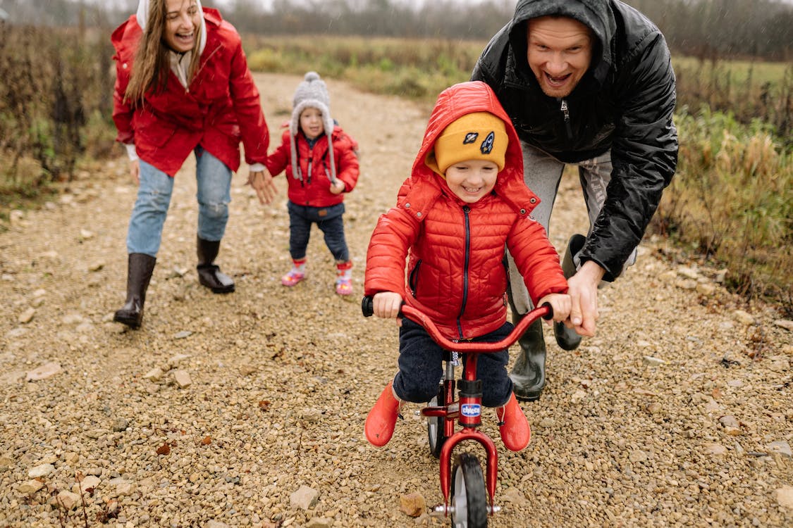 Parents teaching a kid how to ride a bike.